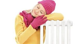 Woman in winter clothing with radiator.