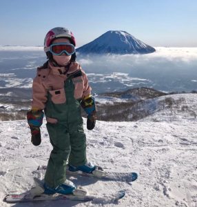 Child skiing with mountain background.