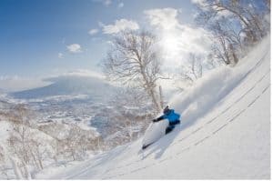 Skier descending snowy slope in winter.
