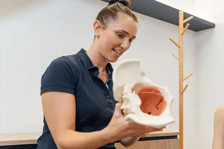 Physiotherapist explaining spinal model.