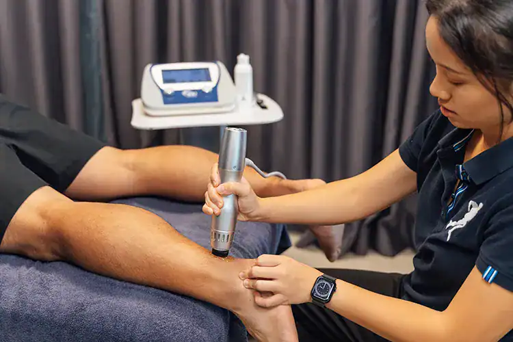 Physiotherapist using shockwave device.