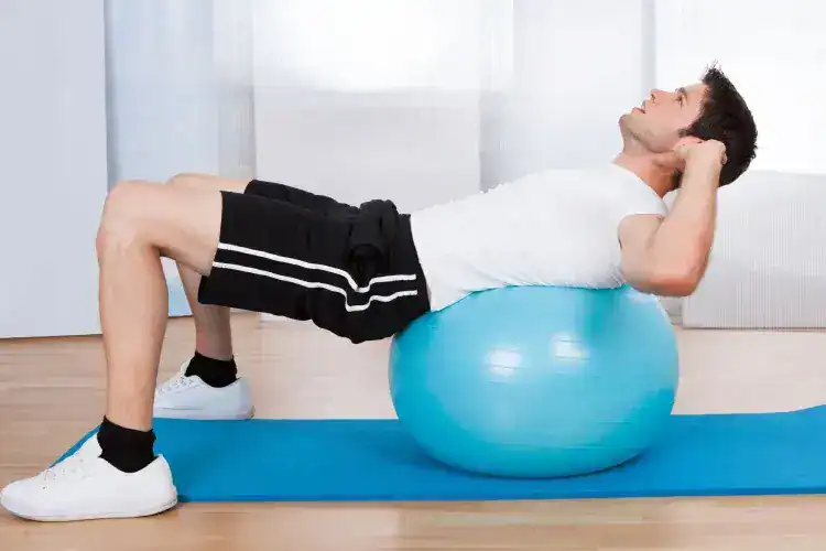 Male exercising on stability ball at gym.